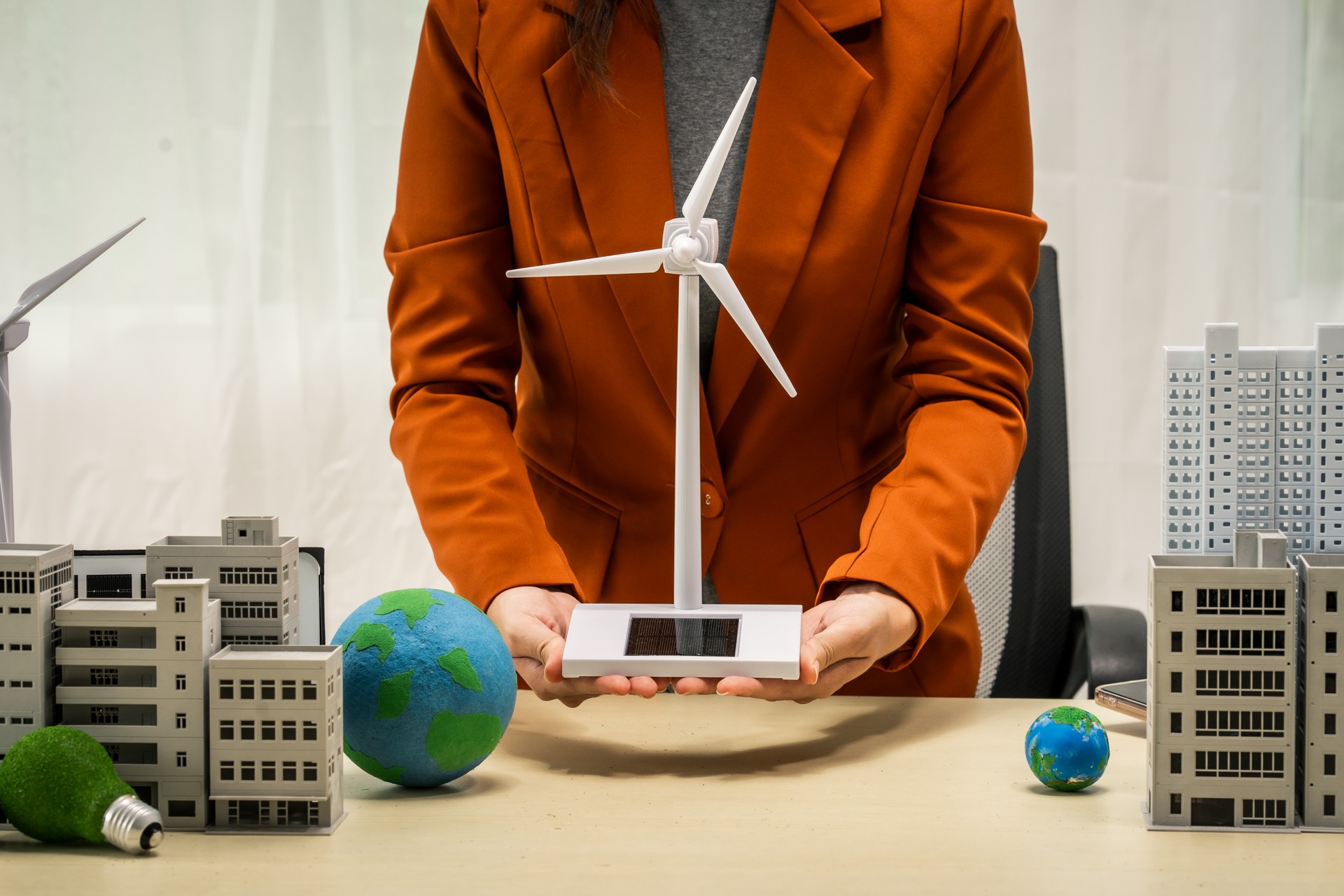 A businesswoman working at a desk in sustainable urban development, promoting eco-friendly futures with green condos and buildings, fostering a clean environment-friendly future.