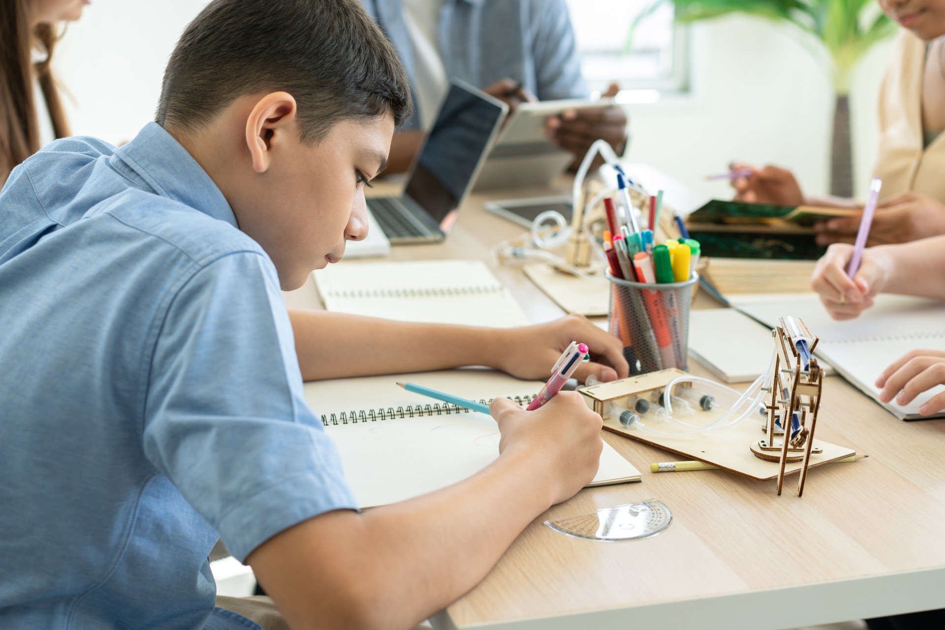 Boy student studying chemistry and doing homework in notebook in science classroom